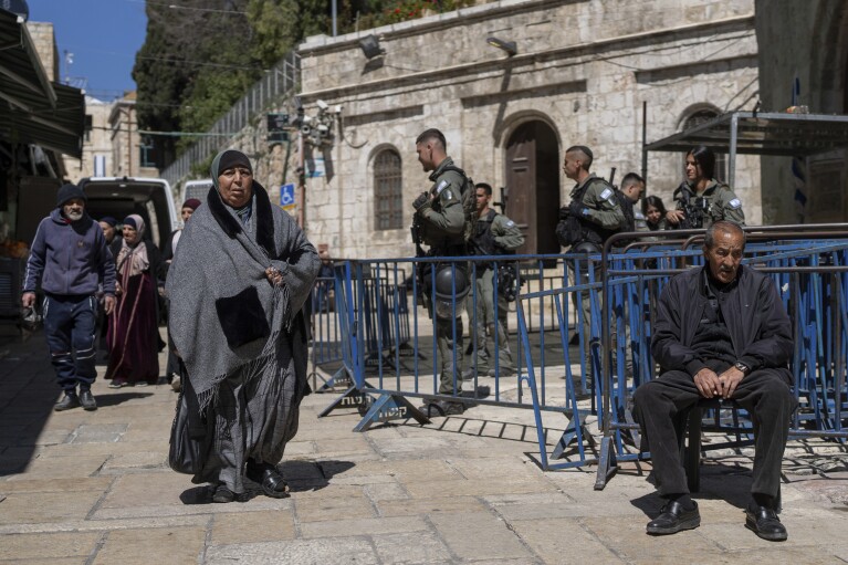 Israeli border police officers stand guard as Palestinians walk by in Jerusalem's Old City on the first day of Ramadan, Monday, March 11, 2024. (AP Photo/Ohad Zwigenberg)