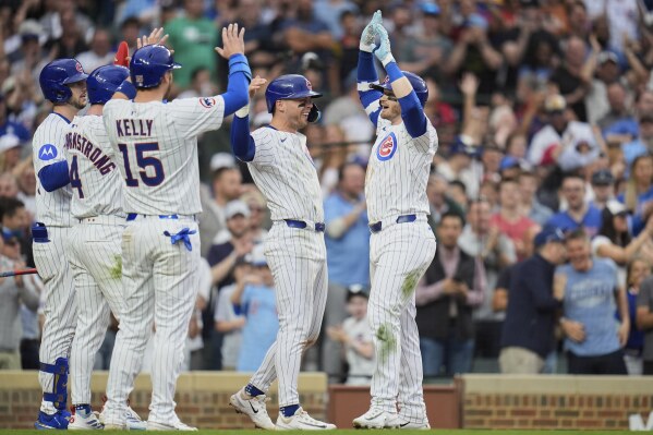 Chicago Cubs' Ian Happ, right, high-fives Nico Hoerner after hitting a grand slam during the seventh inning of a baseball game against the Arizona Diamondbacks, Friday, April 18, 2025, in Chicago. (AP Photo/Erin Hooley)
