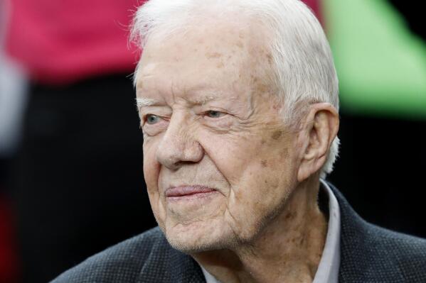 FILE - Former President Jimmy Carter sits on the Atlanta Falcons bench before the first half of an NFL football game between the Atlanta Falcons and the San Diego Chargers, Oct. 23, 2016, in Atlanta. Carter has entered home hospice care after a series of short hospital stays. The Carter Center said in a statement Saturday, Feb. 18, 2023, that Carter, 98, “decided to spend his remaining time at home with his family and receive hospice care instead of additional medical intervention.” (AP Photo/John Bazemore, File)