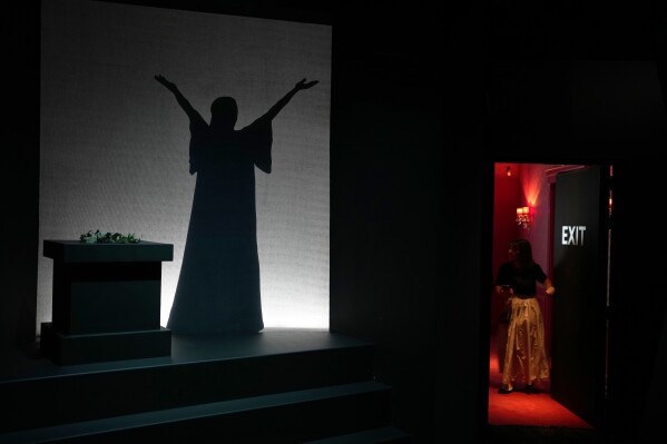 An employe opens a door as the silhouette of Greek Soprano Maria Callas is shown on screen, at the newly established Museum, the first dedicated to the legendary opera star, in Athens, Greece, Wednesday, Oct. 25, 2023. The new museum presents, priceless historical artifacts, including photographs and portraits, rare live recordings, and a unique collection of records and personal items as this year is the 100th anniversary of Maria Callas' birth. (AP Photo/Thanassis Stavrakis)