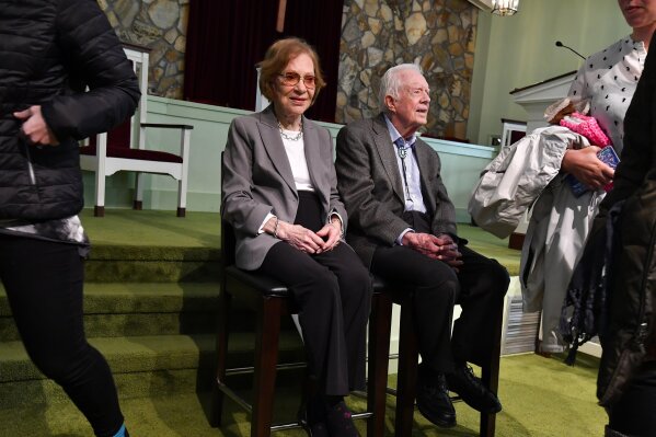 Former U.S. President Jimmy Carter and former first lady Rosalynn Carter, left, sit as guests of Maranatha Baptist Church come and go to have their photo made with them, after Jimmy taught Sunday school there, Sunday, Nov. 3, 2019, in Plains, Ga. (AP Photo/John Amis)