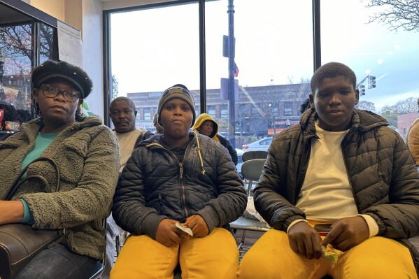 The Alexis family waits in the Immigrant Family Services Institute in Mattapan, Massachusetts on Wednesday, Nov. 15, 2023. The family arrived in Boston a week ago and are struggling to find housing after the state capped the number of family shelter spots and created a wait list. (AP Photo/Michael Casey)