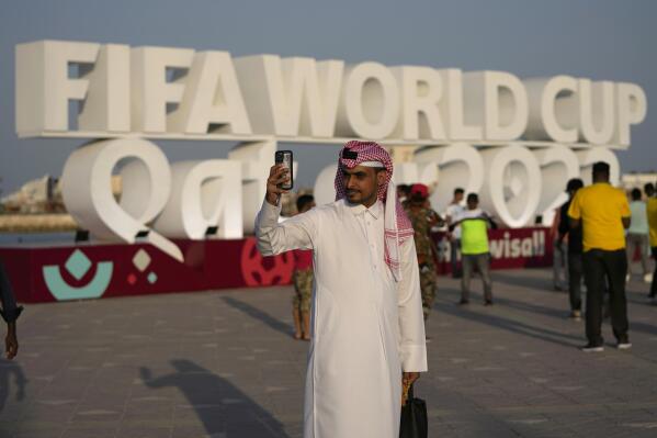 FILE - A man takes a selfie with a sign reading in English" Fifa World Cup, Qatar 2022" at the corniche in Doha, Qatar, Friday, Nov. 11, 2022. With no soccer tradition but billions in oil money, Qatar is the latest Persian Gulf nation using sports to try to burnish its image on the global stage. The host of the 2022 World Cup is smaller than Connecticut and has a population of fewer than 3 million. (AP Photo/Hassan Ammar, File)