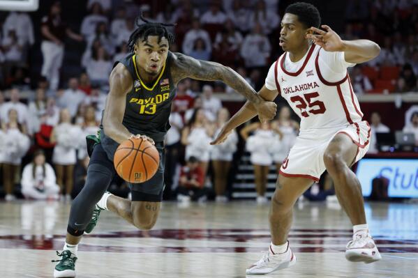 Baylor guard Langston Love (13) drives the ball against Oklahoma guard Grant Sherfield (25) during the first half of an NCAA college basketball game Saturday, Jan. 21, 2023, in Norman, Okla. (AP Photo/Garett Fisbeck)