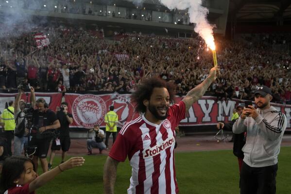Brazilian soccer player Marcelo holds a flare during his presentation by Olympiakos at Georgios Karaiskakis stadium at Piraeus port, near Athens, Greece, Monday, Sept. 5, 2022. Greek soccer club Olympiakos signed Brazilian star Marcelo, the contract is for one year, with an option for an additional year. (AP Photo/Thanassis Stavrakis)