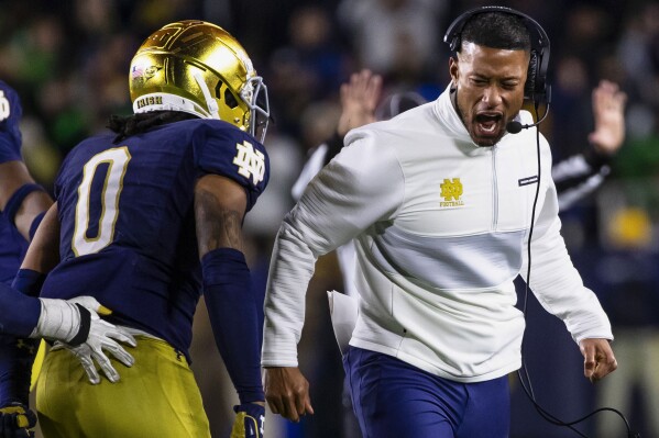 Notre Dame head coach Marcus Freeman celebrates with safety Xavier Watts (0) during the second half of an NCAA college football game against Southern California Saturday, Oct. 14, 2023, in South Bend, Ind. (AP Photo/Michael Caterina)