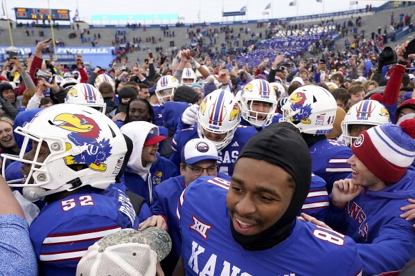 Kansas players celebrate with fans on the field after their NCAA college football game against Oklahoma Saturday, Oct. 28, 2023, in Lawrence, Kan. Kansas won 38-33. (AP Photo/Charlie Riedel)
