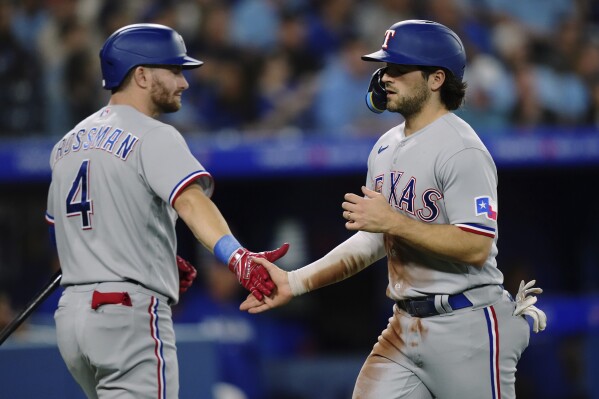Texas Rangers shortstop Josh Smith, right, celebrates with Robbie Grossman after scoring against the Toronto Blue Jays during the seventh inning of a baseball game Tuesday, Sept. 12, 2023, in Toronto. (Nathan Denette/The Canadian Press via AP)