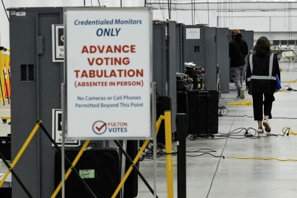 An election worker walks near voting machines at the Fulton County Election Hub and Operation Center, Nov. 5, 2024, in Atlanta. (AP Photo/John Bazemore, File)