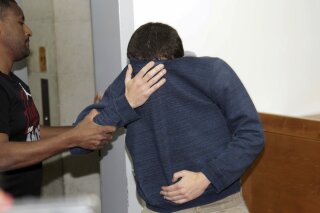 
              A 19-year-old dual U.S.-Israeli citizen covers his face as he is brought to court in Rishon Lezion, Israel, Thursday, March 23, 2017. Israeli police said they have arrested a Jewish Israeli man who is the prime suspect behind a wave of bomb threats against Jewish community centers and other institutions in the United States. The police withheld his identity. (AP Photo/Nir Keidar) ***ISRAEL OUT***
            