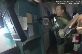 In this image from body-camera footage provided by the Santa Clara County Sheriff’s Office, deputies approach a set of doors with their weapons drawn inside a building at the Santa Clara Valley Transportation Authority bus and rail yard after hearing shots fired from beyond the doors, Wednesday, May 26, 2021, in San Jose, Calif. The newly released footage shows that a gunman who killed nine co-workers at the facility shot himself twice in the head as sheriff’s deputies raced into the building. A face, background right, has been blurred by the source. (Santa Clara County Sheriff’s Office via AP)