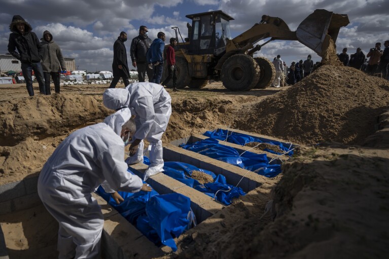 Palestinians bury the bodies of people who were killed in fighting with Israel and returned to Gaza by the Israeli military, during a mass funeral in Rafah, Gaza Strip, Tuesday, Jan. 30, 2024. U.S. and Mideast mediators appeared optimistic in recent days that they are closing in on a deal for a two-month cease-fire in Gaza and the release of over 100 hostages held by Hamas. But on Tuesday, Israeli Prime Minister Benjamin Netanyahu rejected the militant group's two main demands — that Israel withdraw its forces from Gaza and release thousands of Palestinian prisoners — indicating that the gap between the two sides remains wide. (AP Photo/Fatima Shbair)