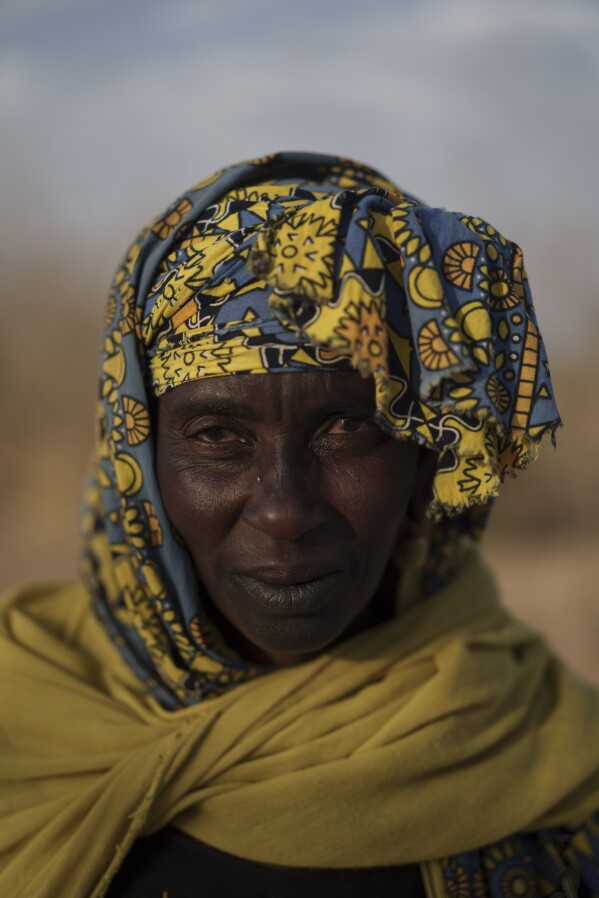 Maary Kalidou Ndiaye stands for a portrait in the village of Yawara Dieri, in the Matam region of Senegal, Saturday, April 15, 2023. The 50-year-old wife of Amadou Ndiaye says some of her main tasks are to take care of the food, fetch water, and prepare the donkeys to carry the family's belongings. She wakes up every day early in the morning to milk the cows, prepare breakfast and fetch water. "Moving around all the time and every day loading and unloading your belongings is exhausting!", she says. (AP Photo/Leo Correa)
