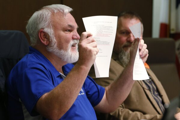 In a Monday, Dec. 9, 2019 photo, chairman of the Buckingham County Board of Supervisors, Donald Bryan, holds up the Second Amendment Sanctuary City resolution during a meeting of the Board in Buckingham , Va. The board unanimously approved the resolution without taking any public comment. (AP Photo/Steve Helber)
