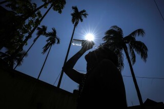 FILE - A man pours water on his face to cool off on a hot summer day in Guwahati, India, Saturday, May 25, 2024. Month after month, global temperatures are setting new records. (AP Photo/Anupam Nath, File)