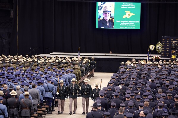 FILE - A likeness of New Hampshire State Police Staff Sgt. Jesse Sherrill appears on a screen, top, during a Celebration of Life service for Sherrill at the SNHU Arena, Nov. 3, 2021, in Manchester, N.H. A Connecticut truck driver who was charged in a highway crash that killed the New Hampshire state trooper has changed his plea to guilty. The crash killed Sherrill in fall 2021. Jay Medeiros of Ashford, Connecticut, was later charged with negligent homicide and reckless conduct. (AP Photo/Steven Senne, file)