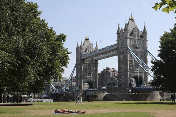 A man sunbathes backdropped by Tower Bridge in London, Tuesday July 19, 2022. Millions of people in Britain woke from the country's warmest-ever night and braced for a day when temperatures could break records. Britain is the latest to suffer a heat wave scorching Europe. (AP Photo/Tony Hicks)