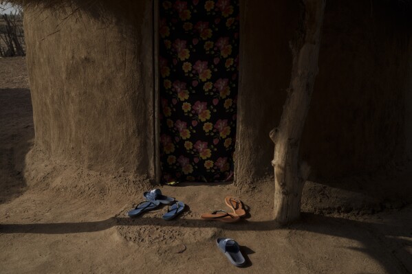 Flip flops are seen at the entrance of a small house at a compound of a family of herders in the village of Anndiare, in the Matam region of Senegal, Wednesday, April 12, 2023. (AP Photo/Leo Correa)