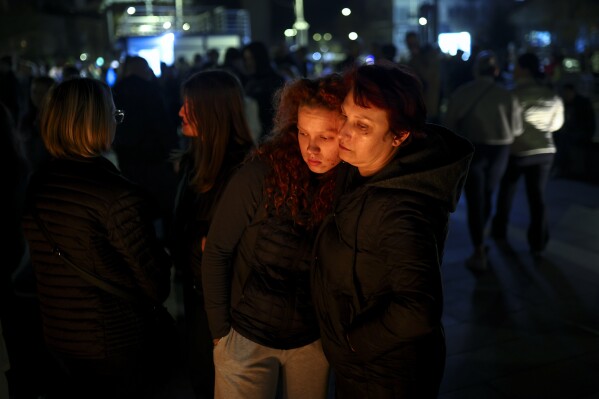 People hug as they wait in lines to light candles in the town of Kocani, North Macedonia, Sunday, March 16, 2025, following a massive fire in the nightclub early Sunday. (AP Photo/Armin Durgut)