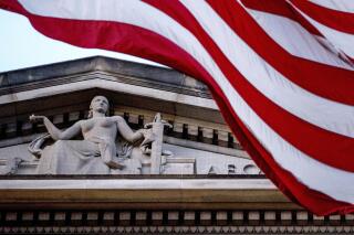 FILE - An American flag flies outside the Department of Justice in Washington,  March 22, 2019. The Justice Department is giving $139 million to police departments across the U.S. as part of a grant program that would bring on more than 1,000 new officers. The grant funding being announced Thursday comes through the Justice Department’s Office of Community Oriented Policing Services and will be awarded to 183 law enforcement agencies. (AP Photo/Andrew Harnik, File)