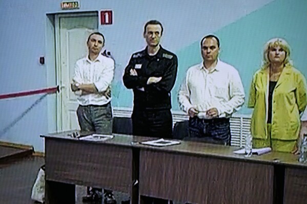 Russian opposition leader Alexei Navalny, 2nd left, and his lawyers Alexander Fedulov, left, Olga Mikhailova, right, and Vadim Kobzev, second right, are seen on a TV screen standing among his lawyers, as he appears in a video link provided by the Russian Federal Penitentiary Service, during a hearing in the colony, in Melekhovo, Vladimir region, about 260 kilometers (163 miles) northeast of Moscow, Russia, on Friday, Aug. 4, 2023.  (AP Photo, File)