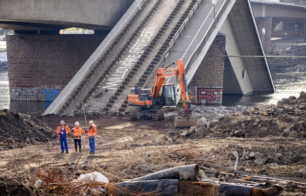 Experts stand in front of an excavator on the partially collapsed Carola Bridge on the Neustadt side during works, in Dresden, Germany, Thursday Jan. 30, 2025. (Robert Michael/dpa via AP, File)