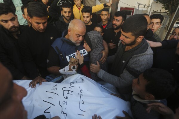 Al Jazeera journalist Wael Dahdouh holds the hand of his son Hamza, who also worked for Al Jazeera and who was killed in an Israeli airstrike in Rafah, Gaza Strip, Sunday, Jan. 7, 2024. Dahdouh lost his wife, two other children, and a grandson earlier in the war and was nearly killed himself. (AP Photo/Hatem Ali)