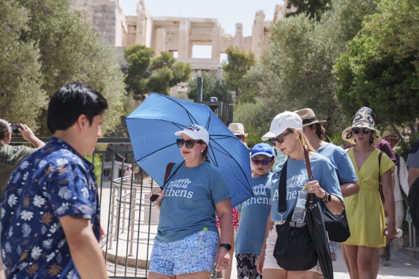 Tourists exit the ancient Acropolis in central Athens, Wednesday, June 12, 2024. The ancient site was closed to the public for five hours due to a heat wave that pushed temperatures to 39 degrees Celsius (102 Fahrenheit) in the capital and even higher in parts of central Greece.(AP Photo/Petros Giannakouris)