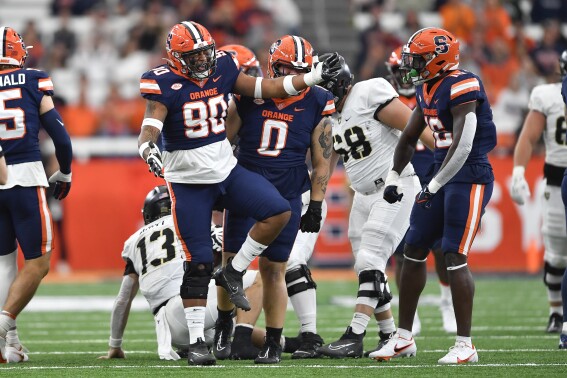 Syracuse defensive lineman Terry Lockett (90) celebrates with linebacker Leon Lowery (16) after a defensive stop during the first half of an NCAA college football game against Army in Syracuse, N.Y., Saturday, Sept. 23, 2023. (AP Photo/Adrian Kraus)