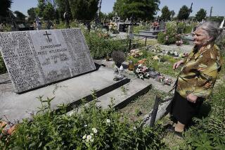 FILE - A woman stands near a mass grave and a monument in the village of Chlaniow, Poland, on June 19, 2013 that holds the bodies of Poles killed in a 1944 attack on the village by the Nazi SS-led Ukrainian Self Defense Legion. Officials in Poland and Ukraine, staunch strategic partners, have unexpectedly exchanged bitter remarks regarding a painful mutual past that includes mass murder. Seeking to calm emotions, an aide to Poland’s President Andrzej Duda said Monday May 22, 2023 that the Poles only wanted the truth and respect for the tens of thousands of Polish victims. (AP Photo/Czarek Sokolowski, File)