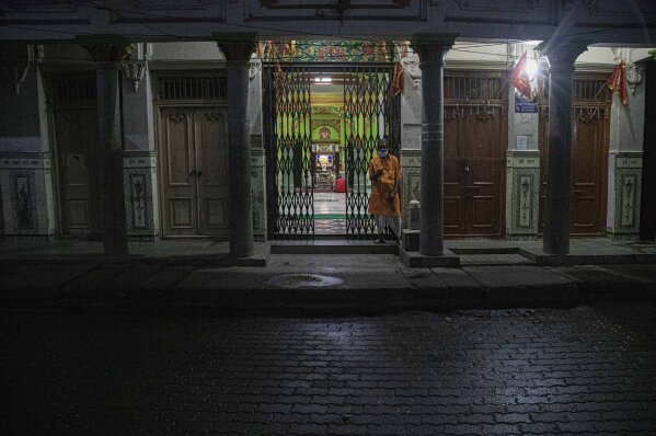 An Indian priest checks his mobile phone outside a Hindu temple during nationwide lockdown in Gauhati, India, Tuesday, May 5, 2020. India's six-week coronavirus lockdown, which was supposed to end on Monday, has been extended for another two weeks, with a few relaxations. Locking down the country's 1.3 billion people has slowed down the spread of the virus, but has come at the enormous cost of upending lives and millions of lost jobs. (AP Photo/Anupam Nath)