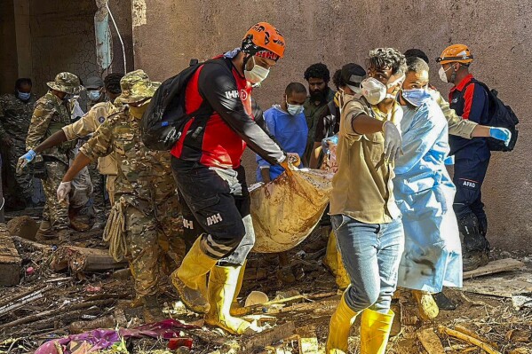 In this photo provided by Turkey's IHH humanitarian aid group, rescuers retrieve the body of a flooding victim in Derna, Libya, Wednesday, Sept.13, 2023. Search teams are combing streets, wrecked buildings, and even the sea to look for bodies in Derna, where the collapse of two dams unleashed a massive flash flood that killed thousands of people. (IHH via AP)
