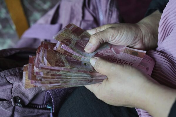 Nina Herlina counts rupiah banknotes she earns from selling livestock ahead of the Eid al-Adha festival, at her stall in Jakarta, Indonesia, Wednesday, June 4, 2025.(AP Photo/Achmad Ibrahim)