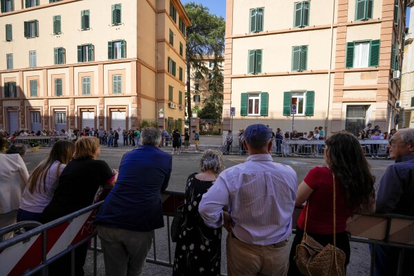 People gather behind barricades in front of an apartment block at Casal Bertone, in far-east Rome, where Pope Francis was expected to pay a visit, Thursday, June 6, 2024. Francis apparently pulled a last-minute switcheroo, after word had spread too much that he was planning to visit the apartment in Casal Bertone, and instead had a surprise meeting with 30 or so families in another building courtyard in the far west neighborhood of Palmarola, at the opposite side of Rome. (AP Photo/Andrew Medichini)