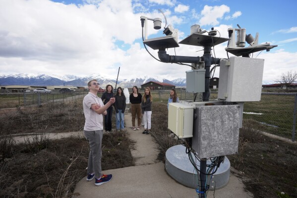 Climate Data Analyst Casey Olson, left, of Utah State University, conducts a tour during a visit to the Utah Climate Center's climate reference station on April 1, 2024, in Logan, Utah. Increasingly, U.S. universities are creating climate change programs to meet demand from students who want to apply their firsthand experience to what they do after high school. (AP Photo/Rick Bowmer)