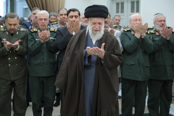 In this photo released by the official website of the office of the Iranian supreme leader, Supreme Leader Ayatollah Ali Khamenei, center, leads a prayer during his meeting with a group of senior military leaders, in Tehran, Iran, Sunday, April 21, 2024. (Office of the Iranian Supreme Leader via AP)