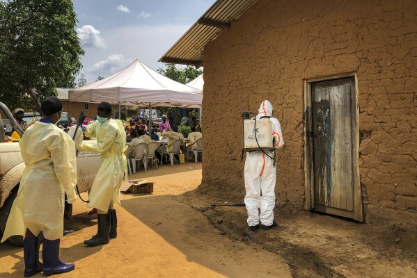 A worker from the World Health Organization (WHO) decontaminates the doorway of a house on a plot where two cases of Ebola were found, in the village of Mabalako, in eastern Congo Monday, June 17, 2019. Health officials in eastern Congo have begun offering vaccinations to all residents in the hotspot of Mabalako whereas previous efforts had only targeted known contacts or those considered to be at high risk. (AP Photo/Al-hadji Kudra Maliro)