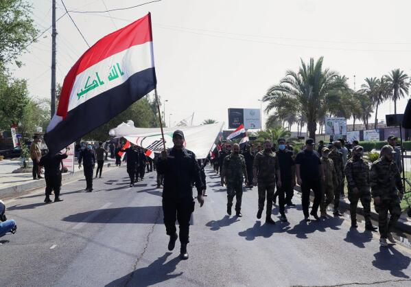 Iran-backed militia fighters march in central Baghdad, Iraq, Tuesday, June 29, 2021. Iraqi Shiite militias are showing a degree of defiance of their patron Iran by escalating rocket and drone attacks on the U.S. presence in the country, militia and Shiite political leaders say. Iran has been pushing the factions to keep calm in Iraq while it holds nuclear negotiations with the United States.  (AP Photo/Khalid Mohammed)
