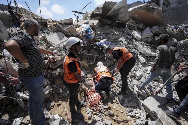 Equipes de resgate palestinas escavam o corpo de um homem sob os escombros de um prédio destruído em um ataque aéreo israelense em Nuseirat, Faixa de Gaza, terça-feira, 14 de maio de 2024. (AP Photo/Abdel Kareem Hana)