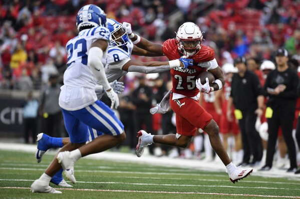 Louisville running back Jawhar Jordan (25) attempts to get away from s Duke linebacker Dorian Mausi (8) and safety Terry Moore (23) during the second half of an NCAA college football game in Louisville, Ky., Saturday, Oct. 28, 2023. (AP Photo/Timothy D. Easley)