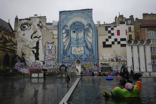 A mosaic by French artist Invader, top right, is seen on a street of Paris, Thursday, Feb. 29, 2024. For the Paris Olympics, it could almost have been a new sport: Score points by scouring France's capital for mosaics that a mystery artist who calls himself "Invader" has cemented to walls across the city, across the world and even had carried aloft to the International Space Station. (AP Photo/Thibault Camus)