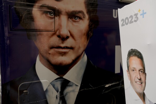 The image of presidential hopeful Javier Milei fills the side of a bus carrying his supporters, left, parked by a wall along the sidewalk where a sign promoting his rival Sergio Massa, during Milei's closing campaign rally in Ezeiza, Buenos Aires Province, Argentina, Wednesday, Nov. 15, 2023. In the run-up to the tightly contested Argentina presidential election runoff Sunday, Nov. 19, Milei is alleging electoral fraud without evidence. (AP Photo/Natacha Pisarenko)