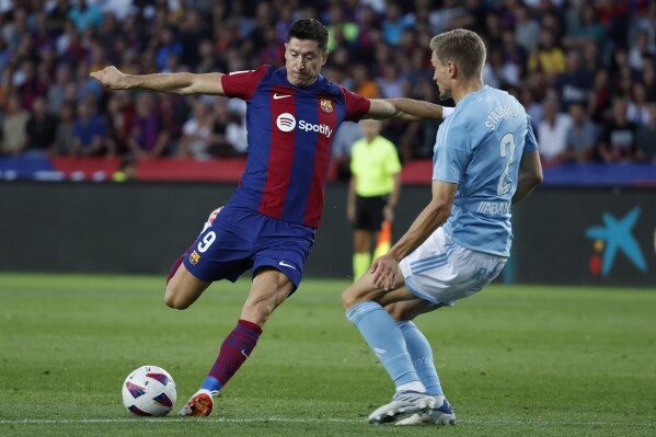 Barcelona's Robert Lewandowski, left, prepares to shoots past Celta's Carl Starfelt during a Spanish La Liga soccer match between Barcelona and Celta at the Olympic Stadium of Montjuic in Barcelona, Spain, Saturday, Sept. 23, 2023. (AP Photo/Joan Monfort)