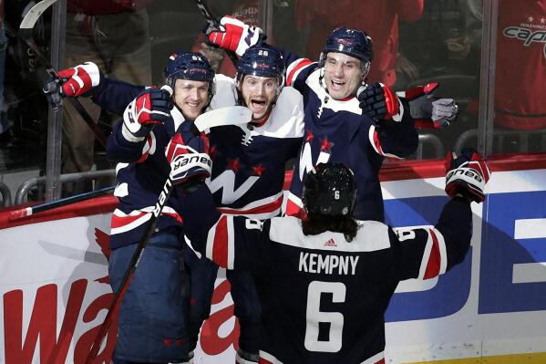 Washington Capitals' Nic Dowd, center, celebrates with teammates Carl Hagelin, left, Garnet Hathaway, right, and Michal Kempny (6) after scoring a goal against Nashville Predators goalie Juuse Saros (74) during the first period of an NHL hockey game, Wednesday, Dec. 29, 2021, in Washington. (AP Photo/Luis M. Alvarez)