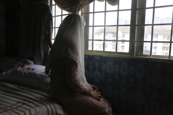 Rohingya child bride, B, age 14, sits on a bed in an apartment in Kuala Lumpur, Malaysia, on Oct. 4, 2023. B came to Malaysia in 2023 to marry an older man. Her husband wants her to get pregnant, but she says she doesn't feel ready. 