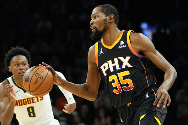 Phoenix Suns forward Kevin Durant (35) moves the ball up court as Denver Nuggets forward Peyton Watson (8) defends during the first half of an NBA basketball game, Friday, Dec. 1, 2023, in Phoenix. (AP Photo/Matt York)
