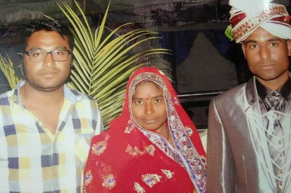 In this Feb. 3, 2014, photo, Joginder Chaudhary, left, and Kapil pose for a picture with their mother Premlata on Kapil's wedding day, in Jhantala, Madhya Pradesh, India. After the virus killed the 27-year-old Chaudhary in late July 2020, his mother wept inconsolably. With her son gone, Premlata Chaudhary said, how could she go on living? Three weeks later, on Aug. 18, the virus took her life, too — yet another number in an unrelenting march toward a woeful milestone. (Courtesy of Kapil Chaudhary via AP)