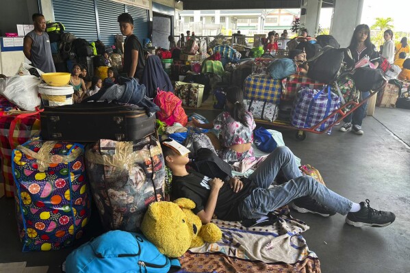 In this photo provided by the Philippine Coast Guard, stranded passengers stay at passenger terminal after sea travel was suspended due to Typhoon Doksuri in Manila, Philippines on Tuesday July 25, 2023. The powerful typhoon blew closer to the northern Philippines on Tuesday, forcing thousands of evacuations and a halt to sea travel ahead of torrential rains and tidal surges up to 3 meters (nearly 10 feet). (Philippine Coast Guard via AP)