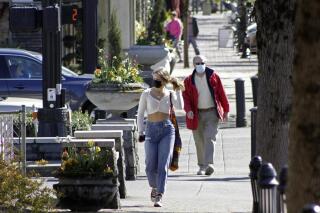 FILE - In this April 11, 2021, file photo, residents wearing masks walk in downtown Lake Oswego, Ore. Oregon Gov. Kate Brown said Tuesday, April 27, 2021 rising COVID-19 hospitalizations threaten to overwhelm doctors and she is moving 15 counties into extreme risk category, which imposes restrictions including banning indoor restaurant dining. (AP Photo/Gillian Flaccus, File)