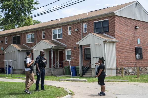 Resident Ashley Johnson speaks with Baltimore Police officers about the mass shooting incident in the Southern District of Baltimore, Monday, July 3, 2023. Police say a number of people were killed and dozens of others were wounded in a shooting that took place during a block party just after midnight on Sunday. (AP Photo/Nathan Howard)